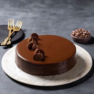 Luxurious Belgian chocolate truffle cake with glossy ganache and chocolate toppings on a white marble plate