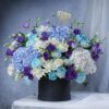 Super Dad floral arrangement with blue hydrangeas, white roses, and purple flowers in black box